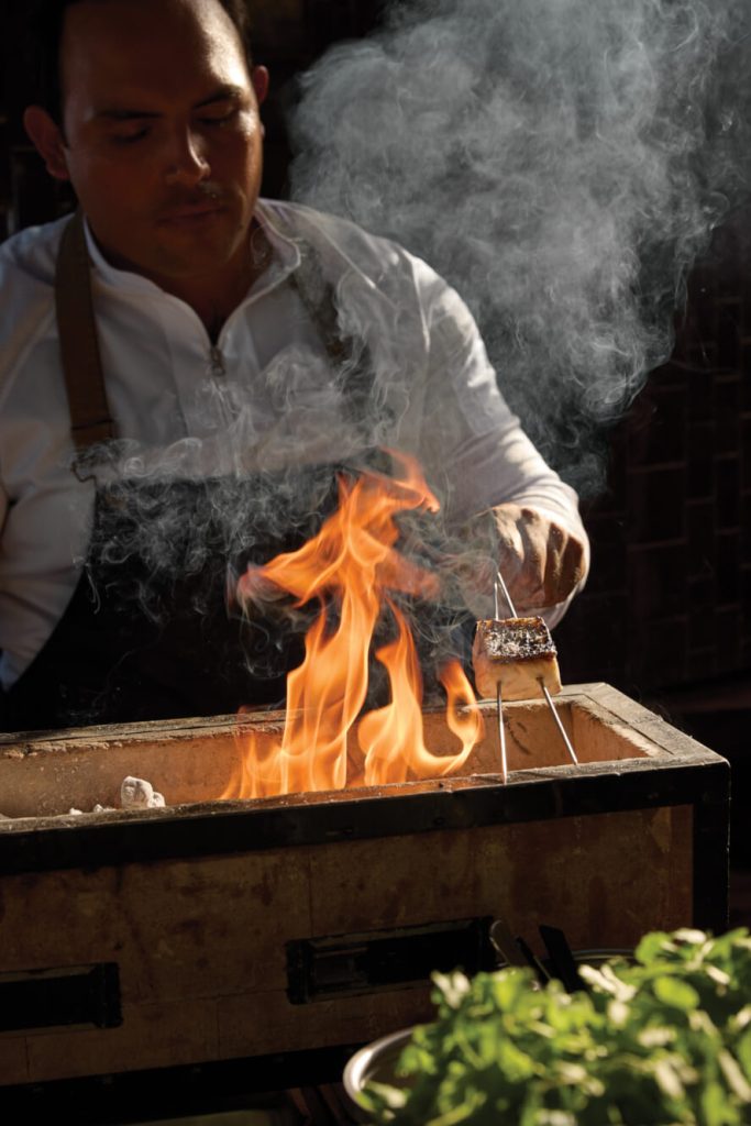 A man cooking fish over an open fire