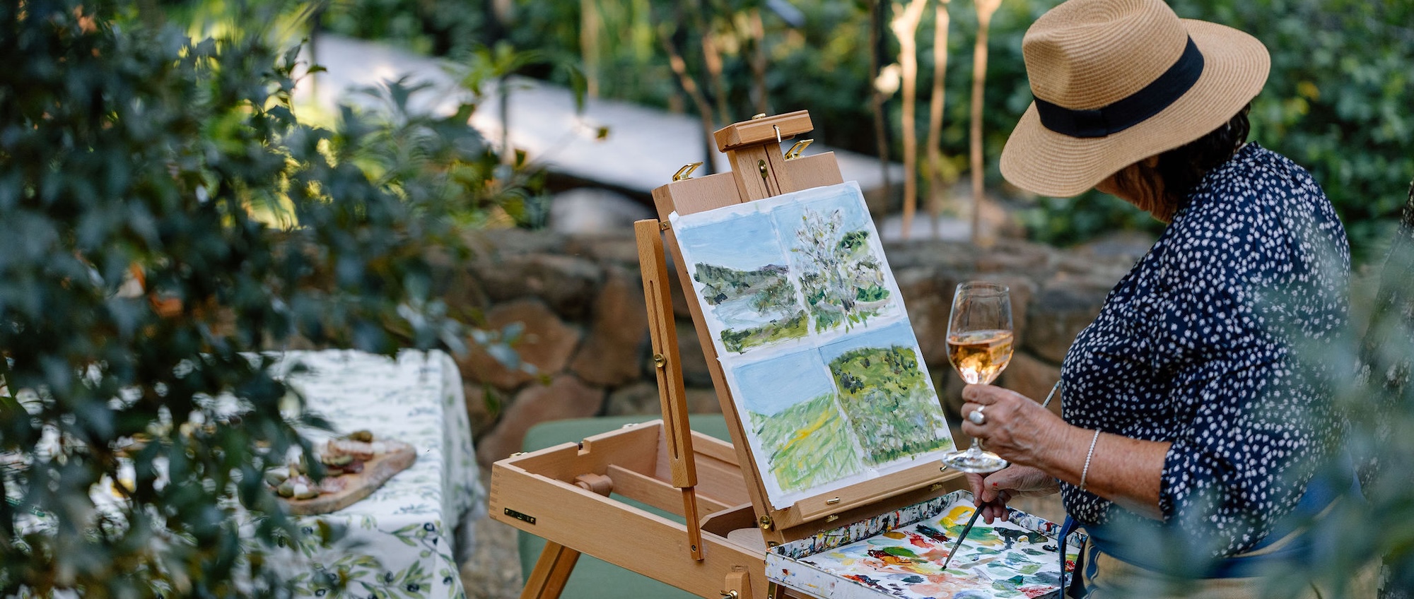 Woman painting picture while drinking glass of wine